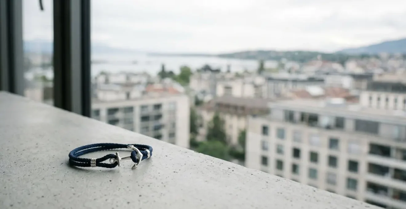 Bracelet ancre marine minimaliste posé sur fond urbain épuré avec espace négatif